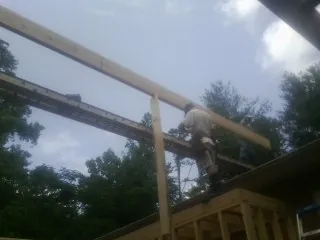 Carpenter setting a ridge beam over a new addition frame — Ice Dam Removal by Roofing Brothers in Goodland