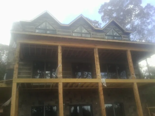 Dormers and porch framing on a large log home under construction — Roof Coating work by our crew in Goodland