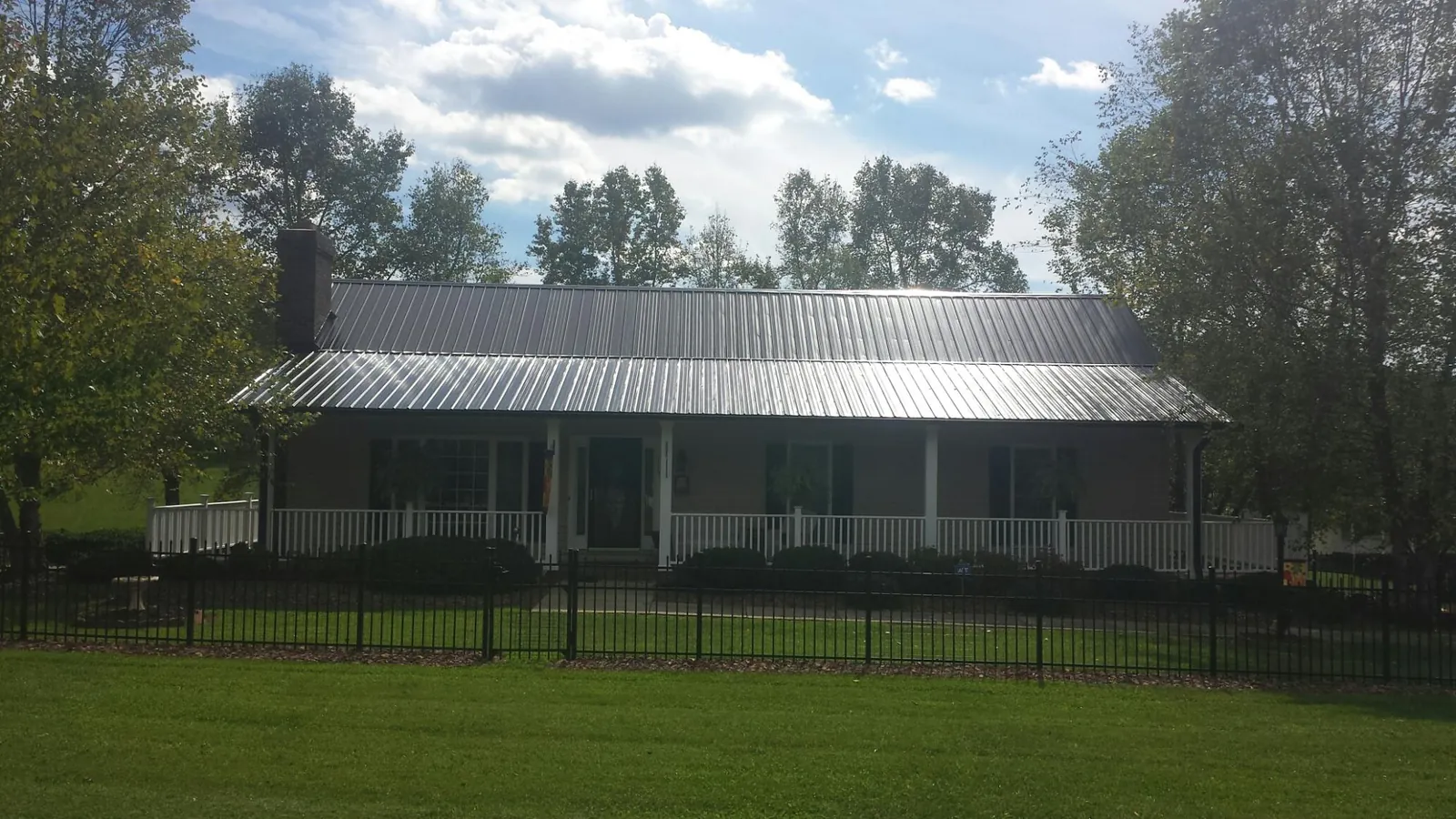Gray metal roof on a brick ranch with a full width front porch — Gutter Guard Installation work by our crew in Goodland