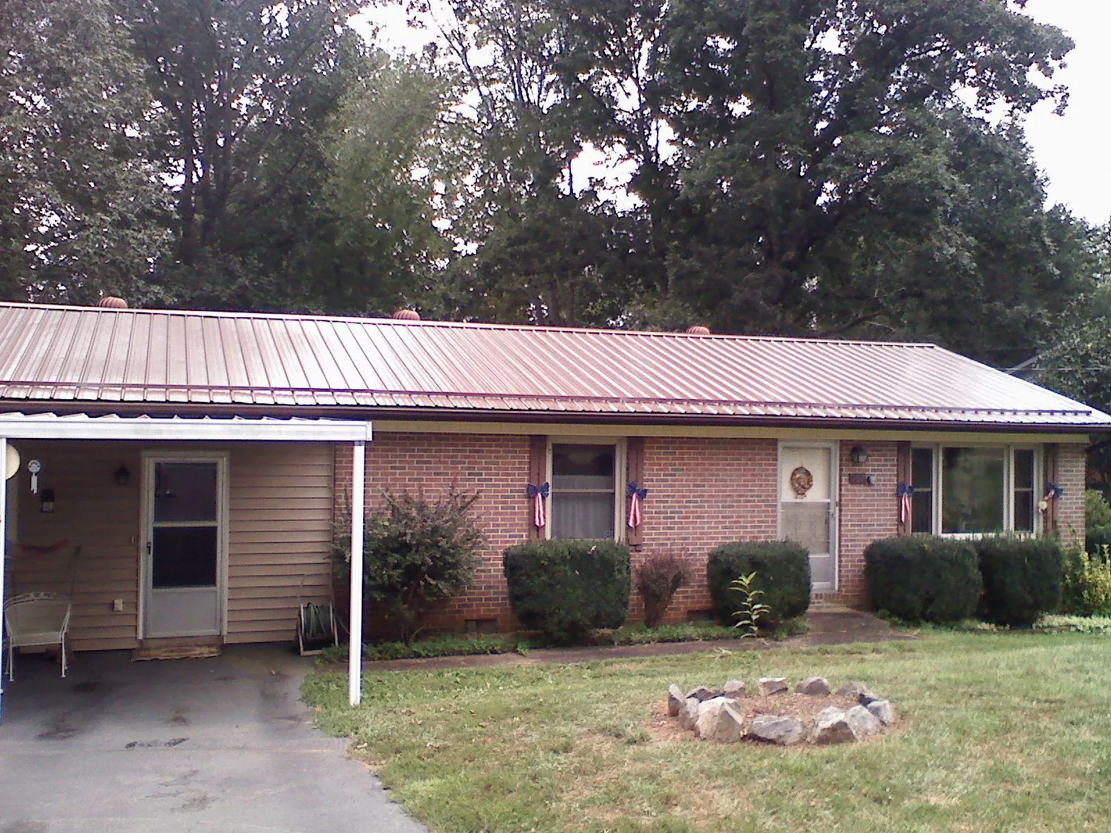 Bronze metal roof and carport on a brick ranch home — Roof Repair work by our crew in Goodland