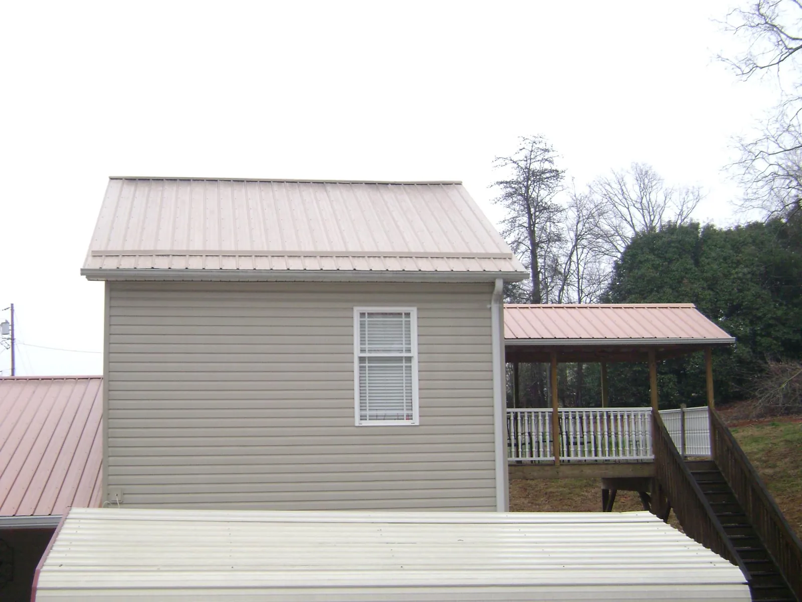 Tan metal roofs on a two story addition and attached porch, from a Roof Replacement job in Goodland