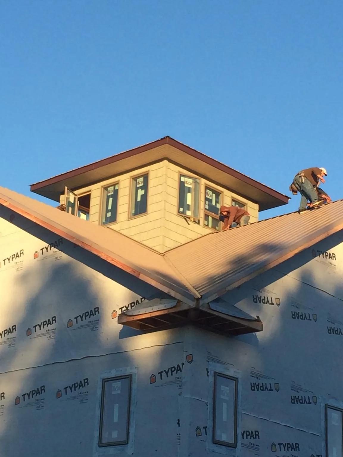 Roofers working around a rooftop cupola on a new metal roof at sunset — Roof Waterproofing in Goodland by Roofing Brothers